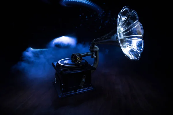 Music concept. Old gramophone on a dark background. Retro gramophone with disc on wooden table with toned backlight. Selective focus