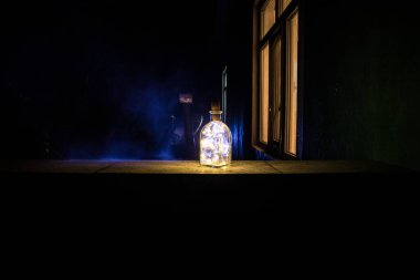 Bahçede gece ışığı olan güzel bir şişe manzarası. Lamba sihirli toz iksiri ormanda şişe içinde. Uzun pozlu çekim. Seçici odak