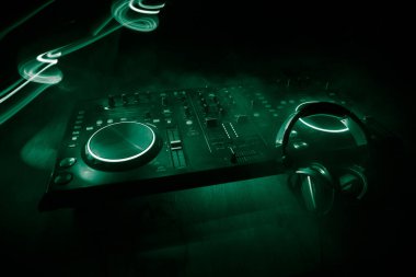 Kulüp müzik konsepti. DJ konsol masası renkli ışıkla karanlıkta DJ karıştırma masası. Karışık ekipman eğlence DJ istasyonu. Seçici odak