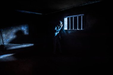 Hapisteki adam demir parmaklıklar arkasında. Eski edepsiz hapishane minyatürü. Karanlık hapishane iç dekorasyonu. Seçici odak