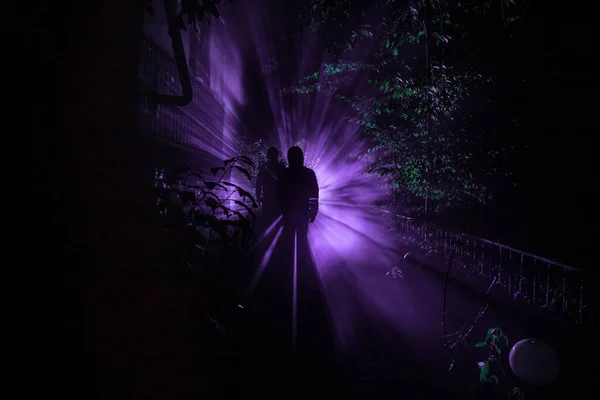 Silhouette of person standing in the dark forest with light. Horror halloween concept. strange silhouette in a dark spooky forest at night