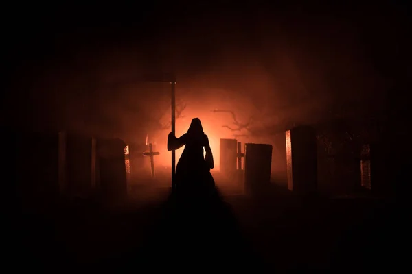 Scary view of grim reaper at cemetery with spooky cloudy sky and fog, Horror Halloween concept. Selective focus