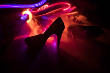 Sanat dekorasyonu. Karanlıkta topuklu kadın ayakkabılarının silueti. Kadın gücü ya da kadın egemenliği kavramı. Seçici odak