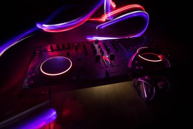 Kulüp müzik konsepti. DJ konsol masası renkli ışıkla karanlıkta DJ karıştırma masası. Karışık ekipman eğlence DJ istasyonu. Seçici odak