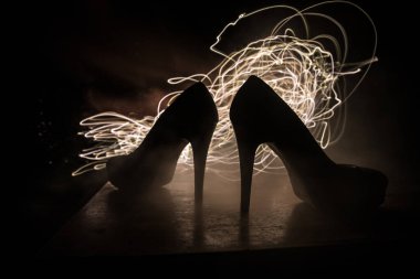 Sanat dekorasyonu. Karanlıkta topuklu kadın ayakkabılarının silueti. Kadın gücü ya da kadın egemenliği kavramı. Seçici odak