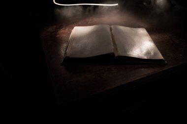 Bir yığın eski kitap. Ahşap masanın üzerinde antika bir kitap. Karanlıkta parlayan bir kitabın etrafında sihirli bir yıldırım. Seçici odak