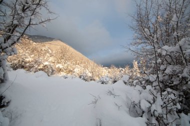 Kış dağlarının manzarasında muhteşem bir günbatımı. Dramatik bir gökyüzü. Azerbaycan doğası. Shaki.