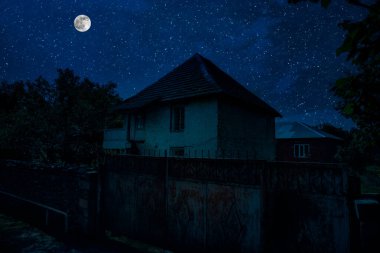 Sisli bir gecede ormanda bir hayaletin olduğu eski bir ev ya da House 'un ayın altında olduğu bir gece sahnesi. Ölü ağaç ormanındaki eski mistik bina..