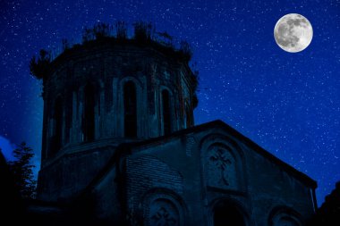 Gotik kilisenin kulesi yıldızlı ve dolunaylı gece gökyüzünün arka planına karşı.