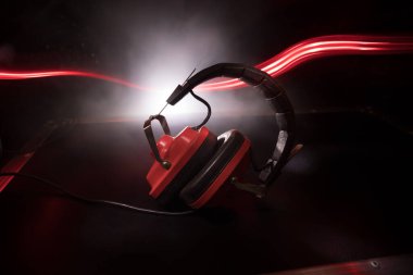 DJ müzik kulübü konsepti. Eskimiş kulaklıkları koyu arka planda renkli ışıkla kapat. Seçici odak