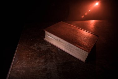 Bir yığın eski kitap. Ahşap masanın üzerinde antika bir kitap. Karanlıkta parlayan bir kitabın etrafında sihirli bir yıldırım. Seçici odak