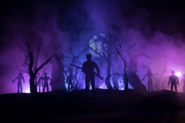 Zombi saldırısına karşı silahlı bir adam. Zombi kıyameti. Ormandaki bulanık zombilerin korkunç görüntüsü ve sisli, ürkütücü bulutlu gökyüzü. Korku Cadılar Bayramı konsepti.