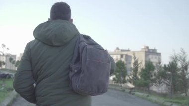 Yalnız bir adam cüzdanı sırt çantasından düşen boş bir caddede yürüyor.