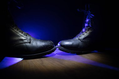 Savaş konsepti. Koyu renkli sisli bir geçmişi olan eski bir asker ayakkabısı. Ülkeler arasında yaratıcı çatışma kavramı, askeri saldırganlık. Seçici odak