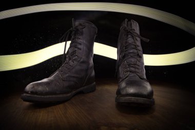 Savaş konsepti. Koyu renkli sisli bir geçmişi olan eski bir asker ayakkabısı. Yaratıcı askeri saldırganlık kavramı. Seçici odak