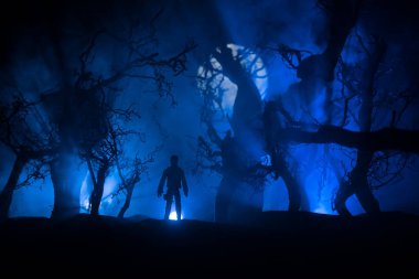 Karanlık ormanda duran bir insan silueti. Korku Cadılar Bayramı konsepti. Gecenin karanlığında ürkütücü bir ormanda tuhaf bir siluet.