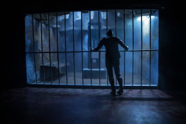 Uygulama kavramı. Eski hapishanede idam cezası giyotini minyatürü. Eski hapishane parmaklıkları hücre kilidi. Hapisteki adam. Karanlıkta Giyotin ölçeği modelinin korkunç görünümü