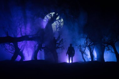 Karanlık ormanda duran bir insan silueti. Korku Cadılar Bayramı konsepti. Gecenin karanlığında ürkütücü bir ormanda tuhaf bir siluet.