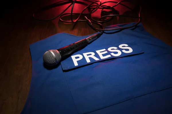 Media Journalism Global Daily News Content Concept. Blue journalist (press) vest in dark with backlight and fog. Media microphone on journalist vest. Selective focus