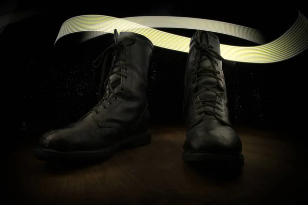 War concept. Old military shoe in a dark toned foggy background. Creative concept of military aggression. Selective focus