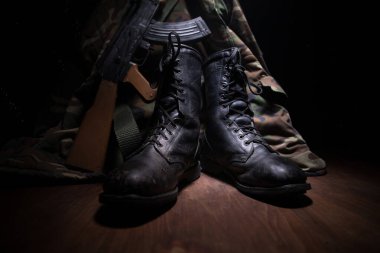 Savaş konsepti. Koyu renkli sisli bir geçmişi olan eski bir asker ayakkabısı. Yaratıcı askeri saldırganlık kavramı. Seçici odak