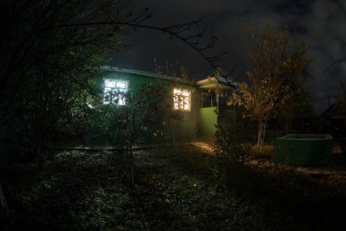 Geceleri ormanda bir hayaletin olduğu eski bir ev ya da terk edilmiş bir korku evi. Ölü ağaç ormanındaki eski mistik bina. Gerçeküstü ışıklar. Korku Cadılar Bayramı konsepti