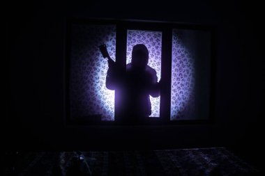 Kapalı cam bir kapıdan geçen, bilinmeyen bir gölge figürünün silueti. Geceleri pencerenin önündeki bir insanın silueti. Manyağın bulanık silueti korkunç cadılar bayramı konsepti.