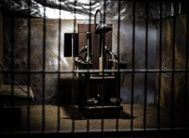 Uygulama kavramı. Eski hapishanenin seçici odak noktasında idam cezası elektrikli sandalye minyatürü. Eski hapishane parmaklıkları hücre kilidi. Yaratıcı sanat dekorasyonu. Karanlıkta elektrikli sandalye ölçeği modeli
