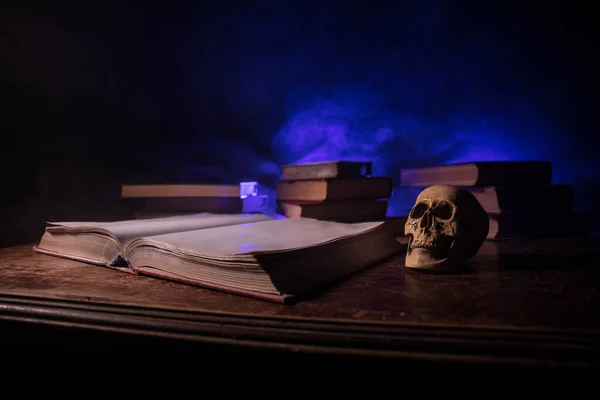 A stack of old books. Vintage book on wooden table. Magic lightning around a glowing book in the room of darkness. Selective focus