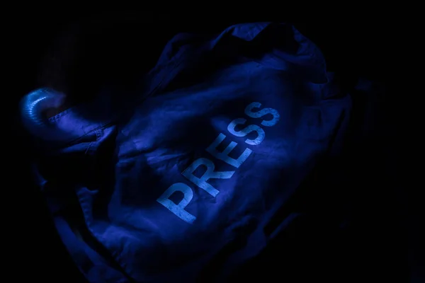 Media Journalism Global Daily News Content Concept. Blue journalist (press) vest in dark with backlight and fog. Selective focus