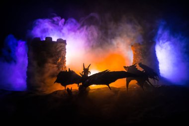 Geceleri ejderhaların bir ortaçağ kalesine saldırdığı fantezi savaş sahnesi. Ejderha ve kahraman askerler arasındaki savaş. Yaratıcı masa dekorasyonu. Seçici odak