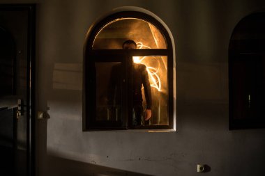 Kapalı cam bir kapıdan geçen, bilinmeyen bir gölge figürünün silueti. Geceleri pencerenin önündeki bir insanın silueti. Manyağın bulanık silueti korkunç cadılar bayramı konsepti.