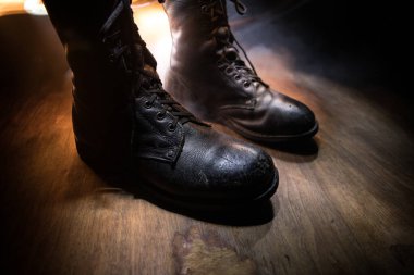 Savaş konsepti. Koyu renkli sisli bir geçmişi olan eski bir asker ayakkabısı. Yaratıcı askeri saldırganlık kavramı. Seçici odak