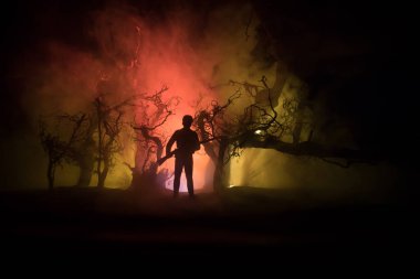 Zombi saldırısına karşı silahlı bir adam. Zombi kıyameti. Ormandaki bulanık zombilerin korkunç görüntüsü ve sisli, ürkütücü bulutlu gökyüzü. Korku Cadılar Bayramı konsepti.