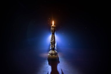 Tek yanan mum. Alevlerin ışığı ve akan mum, koyu arkaplan. Seçici odak