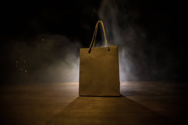 Alışveriş konsepti. Koyu renk masaüstüne saplı kahverengi alışveriş çantası. Seçici odak