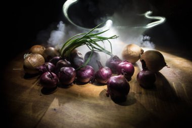 Sebze konsepti. Karanlıkta farklı soğanlar. Seçici odaklanma. Renkli arkaplan.