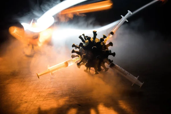 Corona virus Vaccine concept with syringe and green Corona virus novel miniature. Vaccine Concept of fight against coronavirus. Creative decoration with fog and backlight. Selective focus