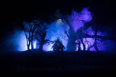 Geceleri ormanda bir hayaletin olduğu eski bir ev ya da sis içinde terk edilmiş bir korku evi. Ölü ağaç ormanındaki eski mistik bina. Geceleri aylı ağaçlar. Gerçeküstü ışıklar. Korku Cadılar Bayramı konsepti