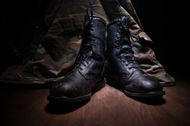 Savaş konsepti. Koyu renkli sisli bir geçmişi olan eski bir asker ayakkabısı. Yaratıcı askeri saldırganlık kavramı. Seçici odak