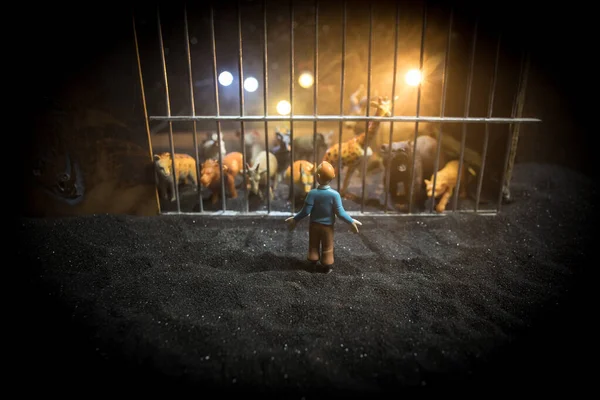 People and animals on opposite sides of the fence concept. Creative decoration with toy figures. Burning colorful background. Selective focus.