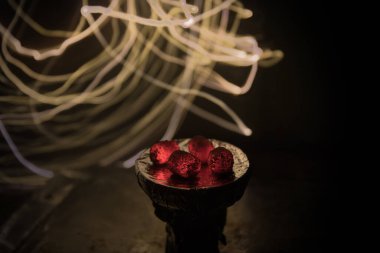 Yakıcı kömür küplerine yakın çekim. Başla. Nargile içtikleri için kasede yanan közler. Karanlık arka planda yaratıcı sanat eserleri. Boşluk. Seçici odak