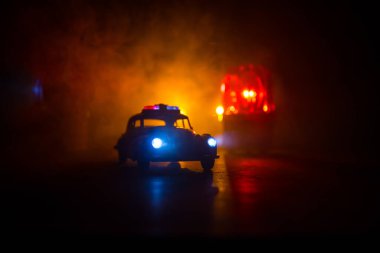 Polis arabası sisli bir arabayı gece takip ediyor. 911 acil durum arabası suç mahalline doğru hızla gidiyor. Yaratıcı dekorasyon. Seçici odak