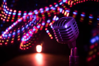 Arka planda arka ışıklandırmalı Retro tarzı mikrofon. Ses, müzik ve karaoke için klasik gümüş mikrofon. Konuşma yayın ekipmanı. Canlı pop, rock müzik performansı. Seçici odak