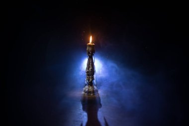 Tek yanan mum. Alevlerin ışığı ve akan mum, koyu arkaplan. Seçici odak