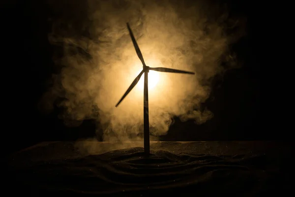 Electricity power in nature or clean energy concept. Wind Turbine producing alternative energy on hill at night. Creative decoration with small miniature. Selective focus