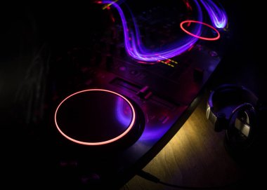 Kulüp müzik konsepti. DJ konsol masası renkli ışıkla karanlıkta DJ karıştırma masası. Karışık ekipman eğlence DJ istasyonu. Seçici odak