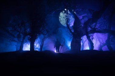 Karanlık ormanda duran bir insan silueti. Korku Cadılar Bayramı konsepti. Gecenin karanlığında ürkütücü bir ormanda tuhaf bir siluet.