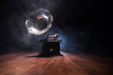 Müzik konsepti. Karanlık bir arka planda eski bir gramofon. Ahşap masanın üzerinde ton lambalı bir disk olan gramofon. Seçici odak