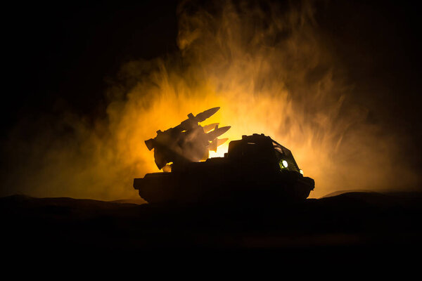 War concept. Battle scene with rocket launcher aimed at gloomy sky at night. Rocket vehicle ready to attack on cloudy war Background. Selective focus